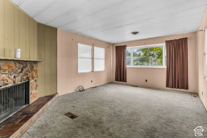 Fireplace featuring a stone facade and a tile hearth, expansive windows, and wall paneling
