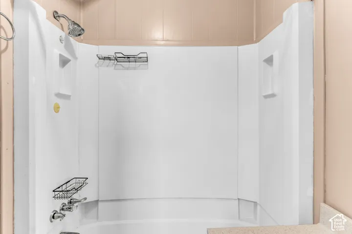 Shower enclosure featuring a white surround, integrated shelving niches, a chrome showerhead, and chrome handle fixtures