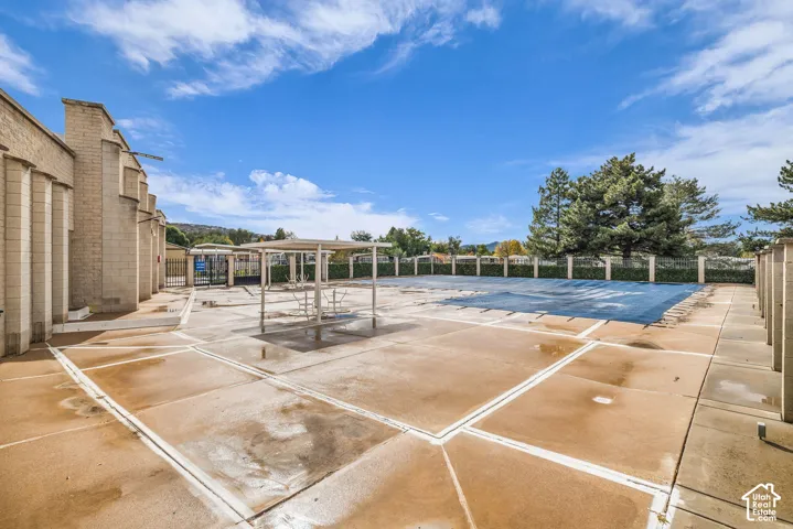 Concrete pool deck featuring a covered patio structure and perimeter fencing