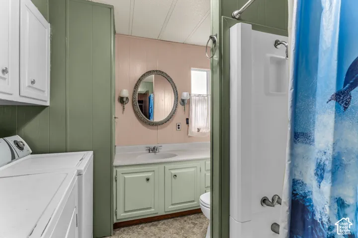Bathroom featuring a built-in vanity with light-colored cabinetry, a neutral solid-surface countertop, an integrated sink, an oval wall-mounted mirror, and a standalone shower unit