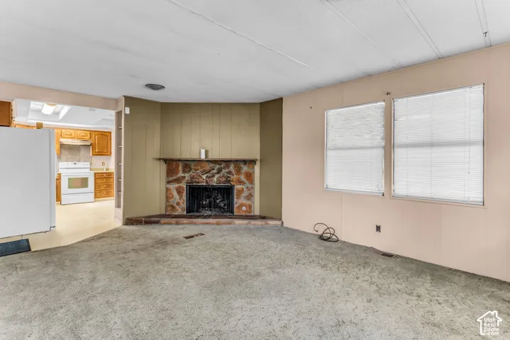 Corner fireplace featuring natural stone masonry, a built-in mantle, and multiple double-pane windows