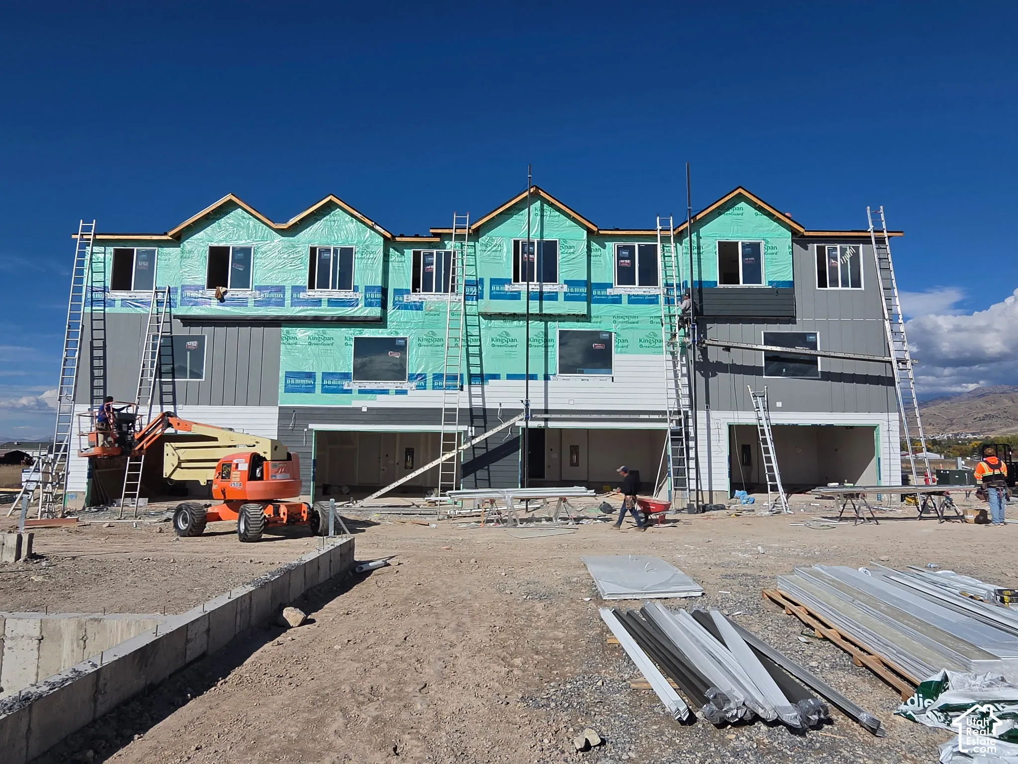 Multi-unit residential structure featuring horizontal and vertical siding, multi-gabled roofline, and integrated multi-car garage bays