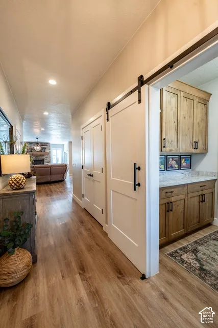 White sliding barn door featuring matte black hardware, wood-finish flooring, and built-in cabinetry with stone-finish countertops