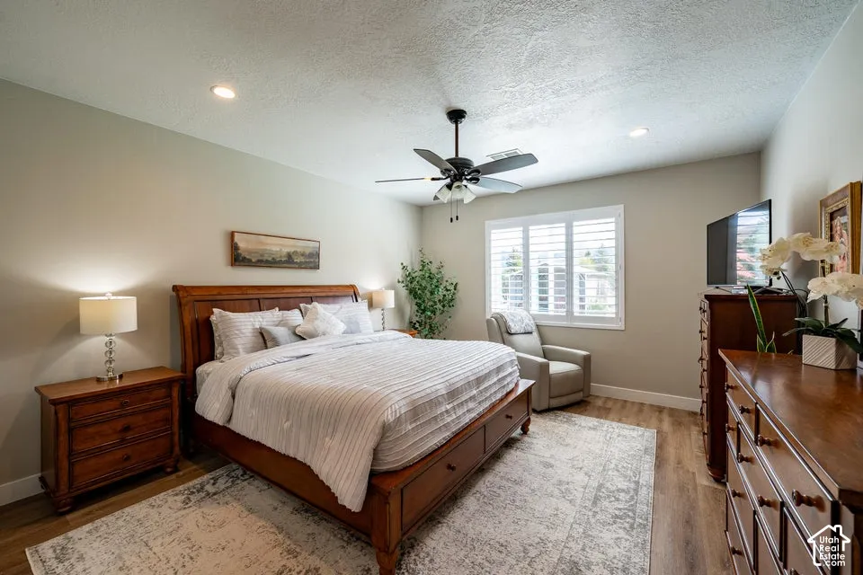 Room featuring wood-finish flooring, recessed lighting, a ceiling fan with integrated light fixture, and plantation shutters