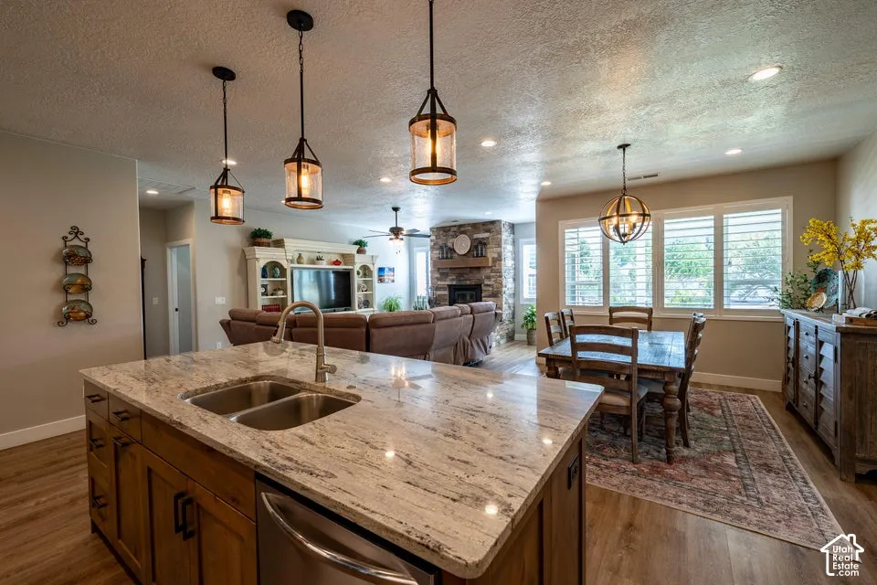 Kitchen island with stone countertop, undermount dual-basin sink, and pendant lighting