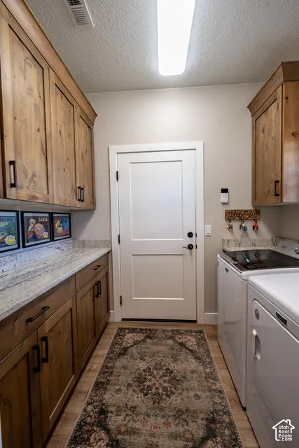 Laundry room featuring stained wood cabinetry, stone countertops, matte black hardware, and an exterior door