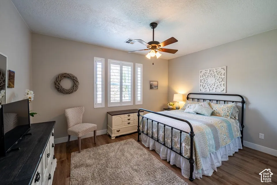 Wood-finish flooring, plantation shutters, and a ceiling fan with integrated lighting
