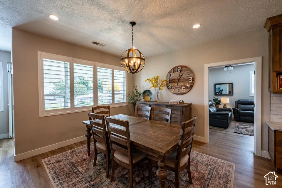 Dining area featuring wood-finish flooring, white plantation shutters, recessed lighting, and a spherical metal pendant chandelier