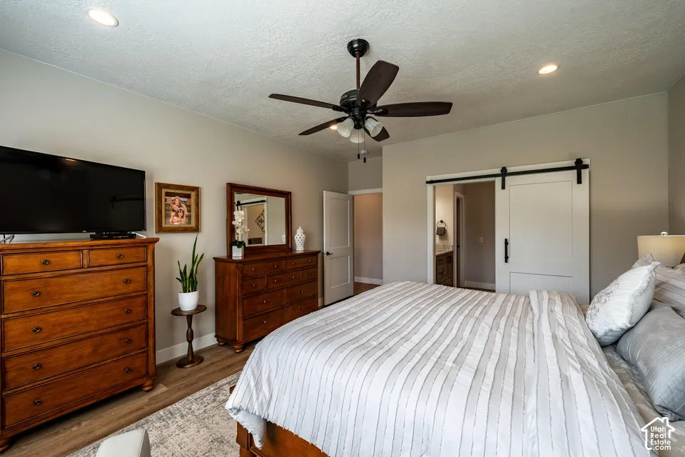 Room featuring wood-finish flooring, a ceiling fan with integrated lighting, recessed lighting, and a white sliding barn door
