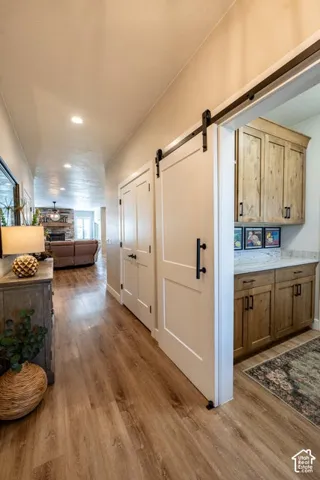 White sliding barn door featuring matte black hardware, wood-finish flooring, and built-in cabinetry with stone-finish countertops