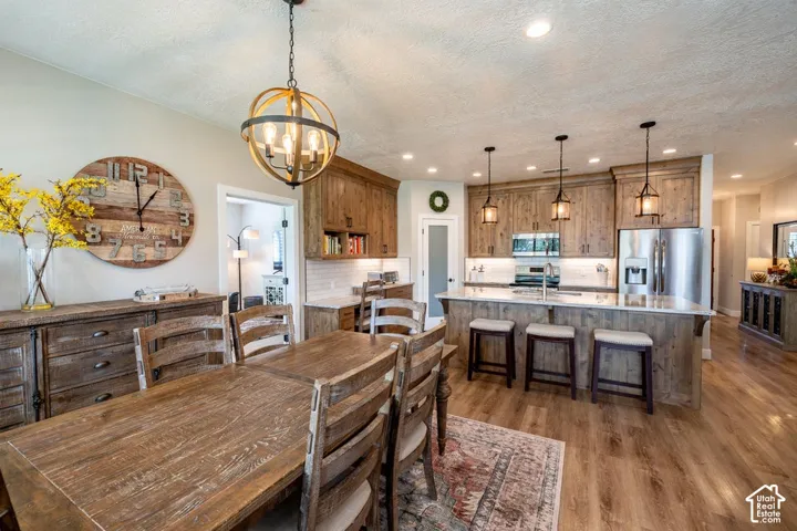 Kitchen featuring wood cabinetry, stone countertops, stainless steel appliances, recessed lighting, and wood-finish flooring