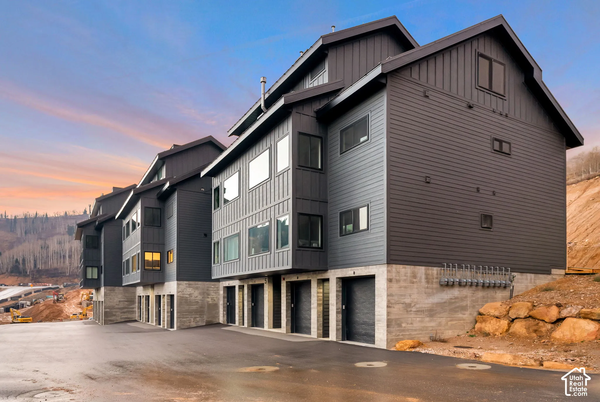 Multi-level exterior featuring dark metal board-and-batten and lap siding, concrete foundation, and garage entry