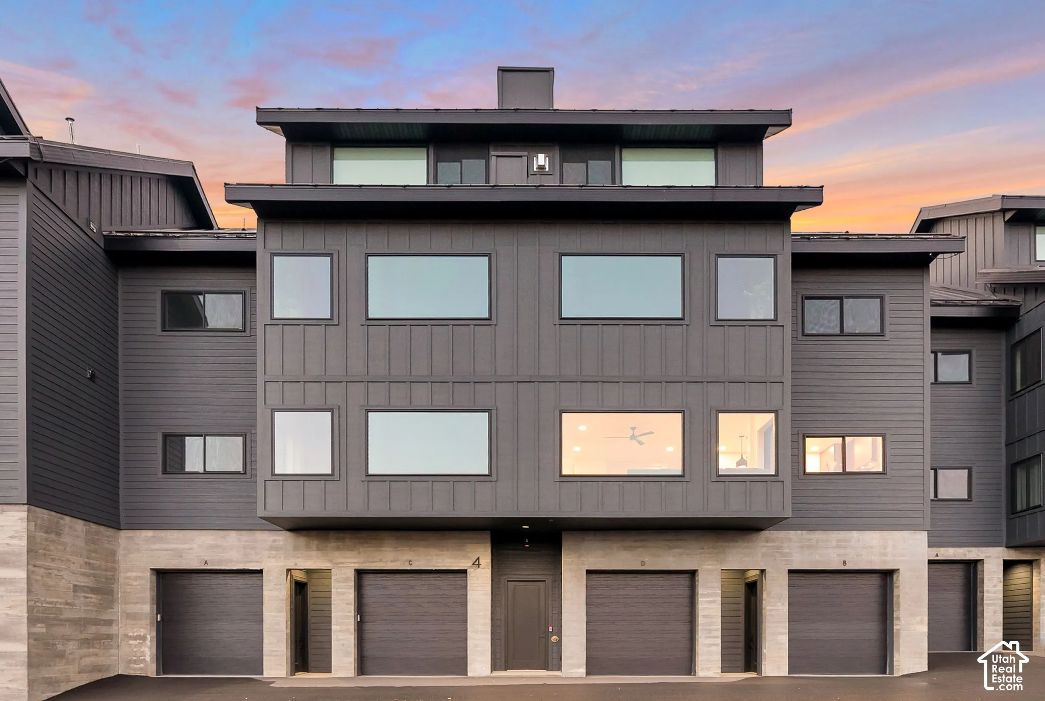 Multi-level exterior featuring dark metal board-and-batten and lap siding, concrete foundation, and garage entry