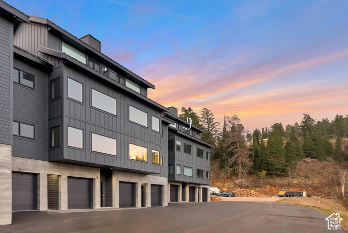 Multi-level exterior featuring dark metal board-and-batten and lap siding, concrete foundation, and garage entry