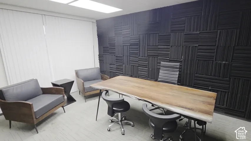 Textured black acoustic wall paneling, recessed lighting, and vertical window blinds