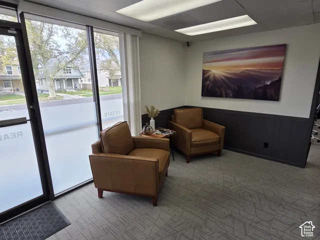Floor-to-ceiling glass paneling, textured patterned carpeting, and charcoal-tone vertical wainscoting complemented by recessed drop-ceiling lighting