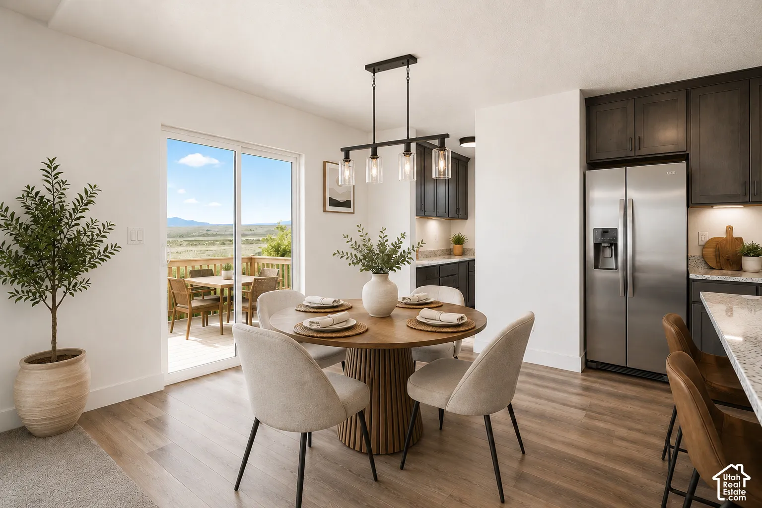 Kitchen featuring dark wood cabinetry, stainless steel refrigerator, stone countertops, wood-finish flooring, and a linear pendant light fixture