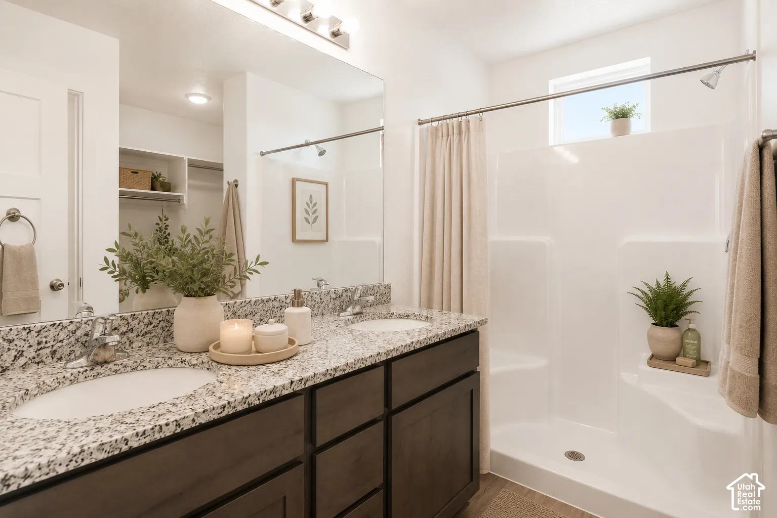 Master bathroom. Dual-sink vanity with speckled stone-finish countertop, dark wood-finish cabinetry, full-width mirror, and a built-in shower-tub combination