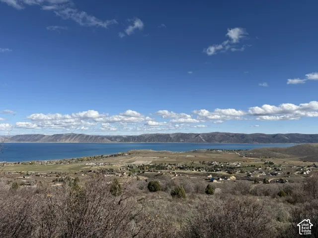 Expansive panoramic scenery featuring a large body of water, rolling mountain ranges, and open terrain