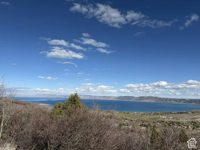 Expansive landscape featuring an elevated perspective of the lake, rugged mountain ranges, and natural brush terrain