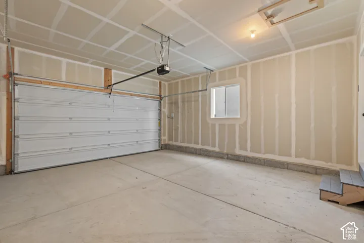 Two-car garage featuring a sectional metal door, concrete flooring, single-pane window, and attic access hatch