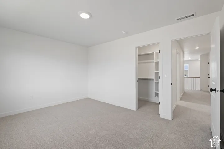 Neutral-toned carpeting, recessed ceiling lighting, and built-in closet shelving