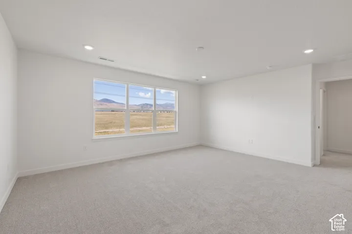 Neutral-toned carpeted flooring, recessed lighting, and a large three-pane window with mountain scenery