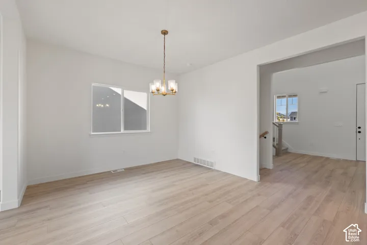 Interior space featuring light-toned wood-finish flooring, neutral walls, and a multi-light brass-finish chandelier