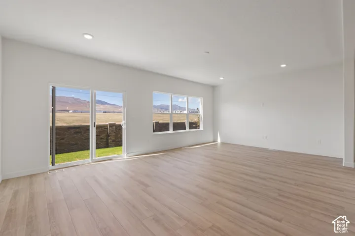 Open-concept interior featuring wood-finish flooring, recessed lighting, sliding glass door, and large picture windows highlighting mountainous scenery