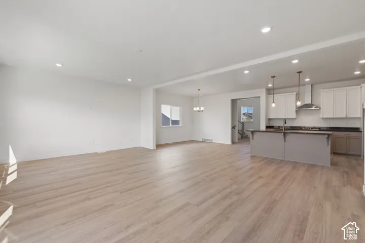 Open-concept interior featuring light wood-finish flooring, recessed lighting, kitchen island with seating, pendant lights, and shaker-style cabinetry
