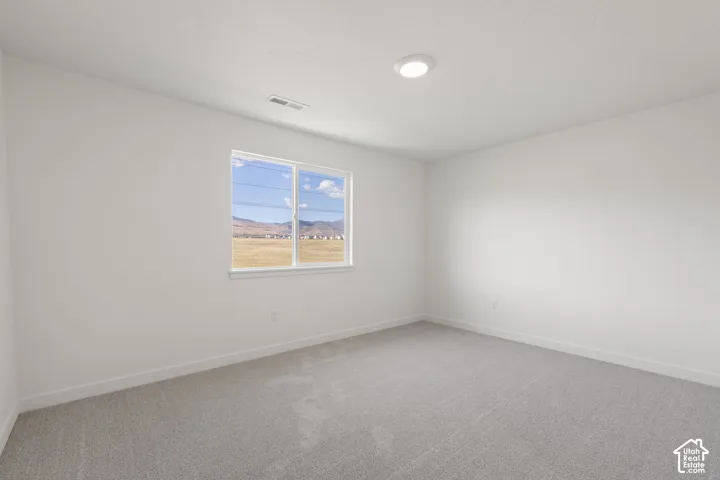Neutral interior featuring carpeted flooring, white walls, a flush-mount ceiling light, and a window with mountain scenery