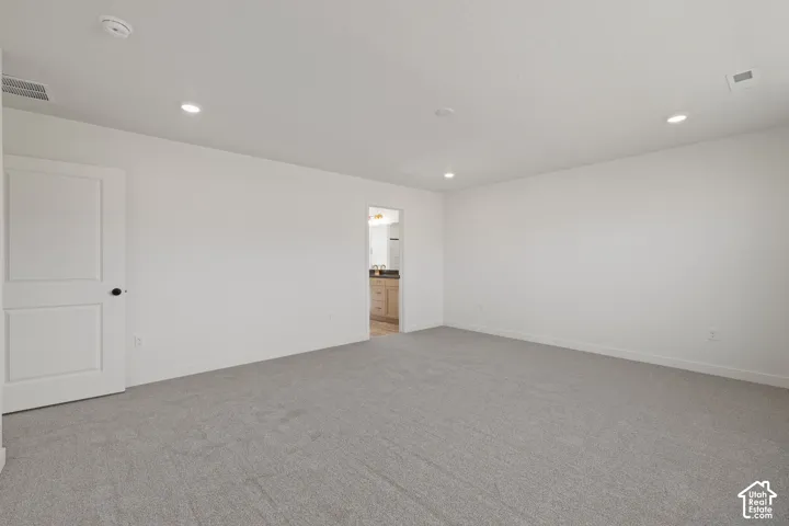 Neutral-toned wall-to-wall carpeting, recessed LED lighting, and a solid-core two-panel interior door