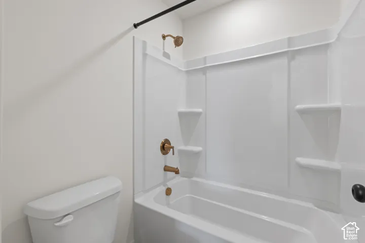 Bathtub and shower surround featuring integrated shelving, complemented by metallic-finish hardware and a high-profile toilet