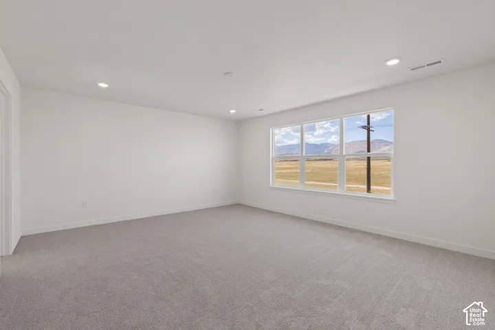 Neutral-toned wall-to-wall carpeting, recessed ceiling lighting, and large picture windows showcasing mountain scenery