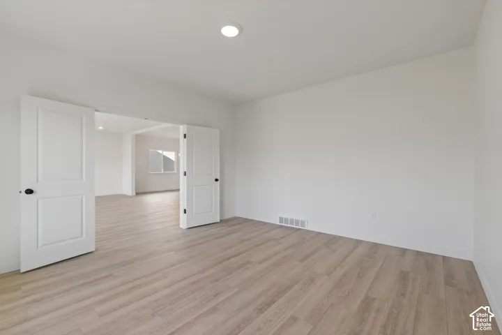 Neutral-toned wood-finish flooring, white walls, recessed ceiling lighting, and double swing doors featuring matte black hardware