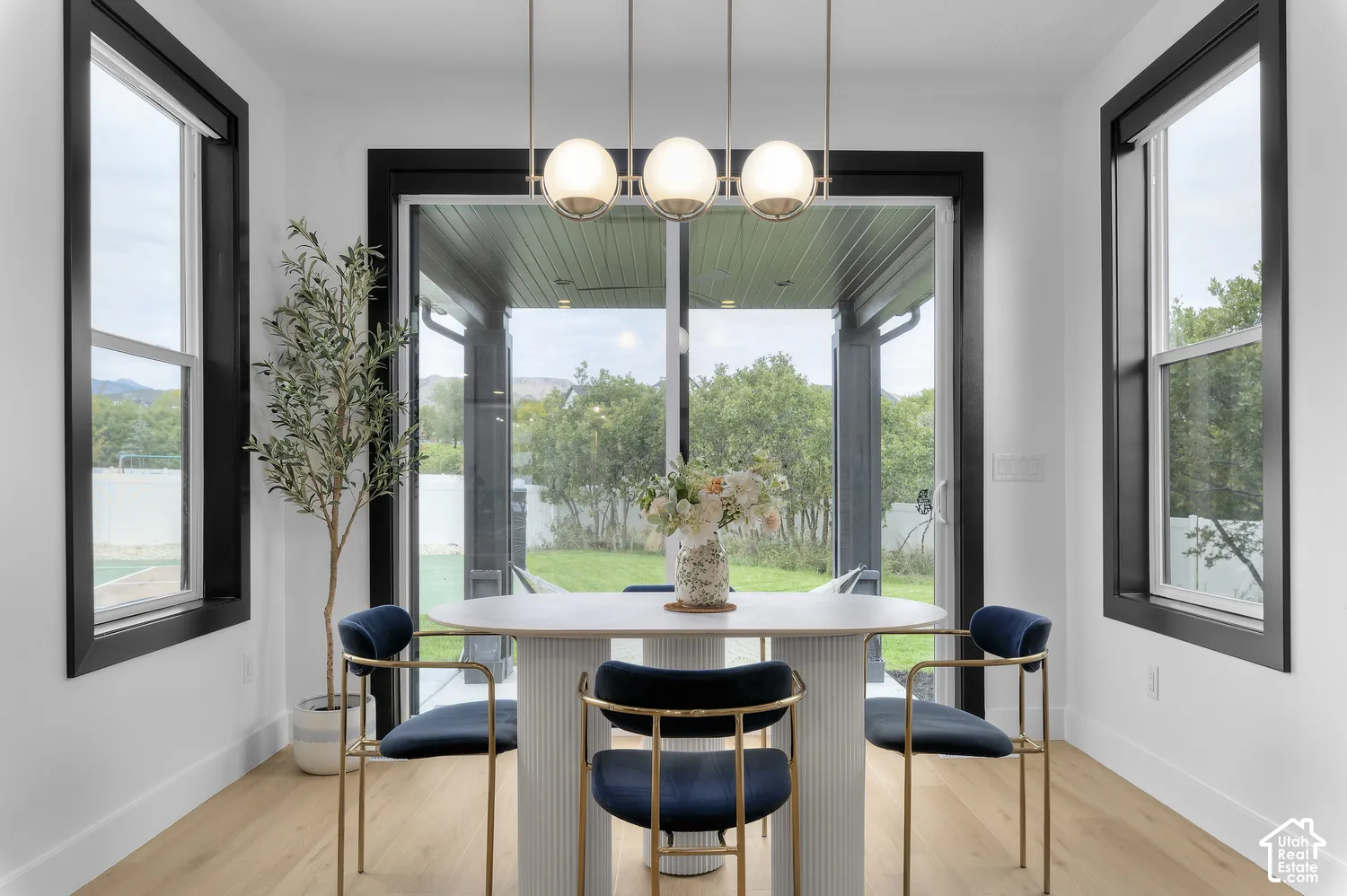 Dining area featuring wood-finish flooring, high-contrast black window trim, a contemporary linear chandelier with frosted globe shades, and sliding glass doors with direct exterior access