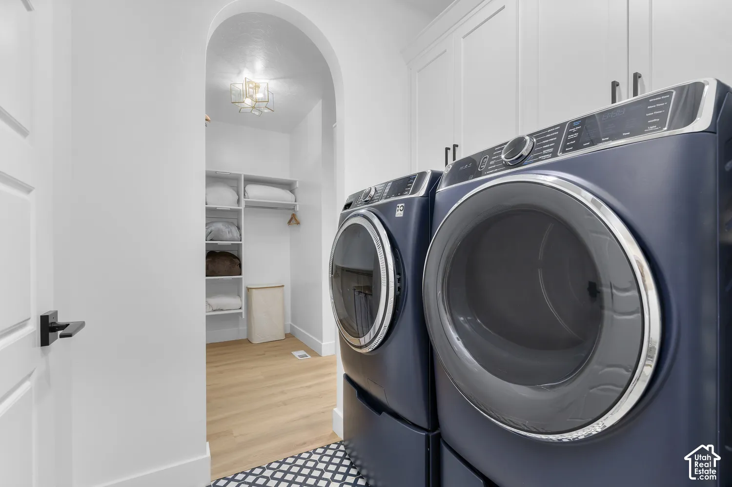 Arched doorway, ceiling-height cabinetry, built-in shelving, and wood-finish flooring