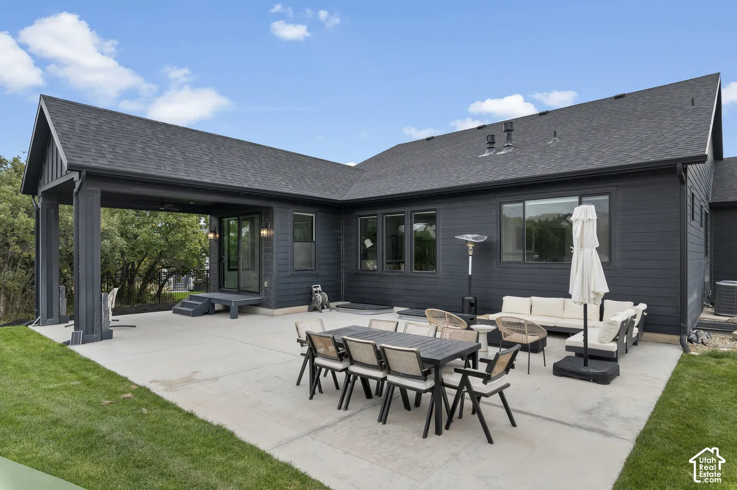 Dark horizontal lap siding exterior featuring a concrete patio, covered outdoor living area, and asphalt shingle roof