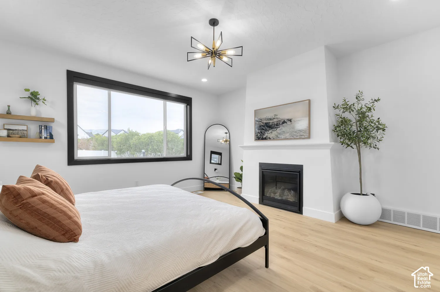Room featuring wood-finish flooring, a fireplace with a white mantel, a geometric starburst light fixture, and large windows with black trim