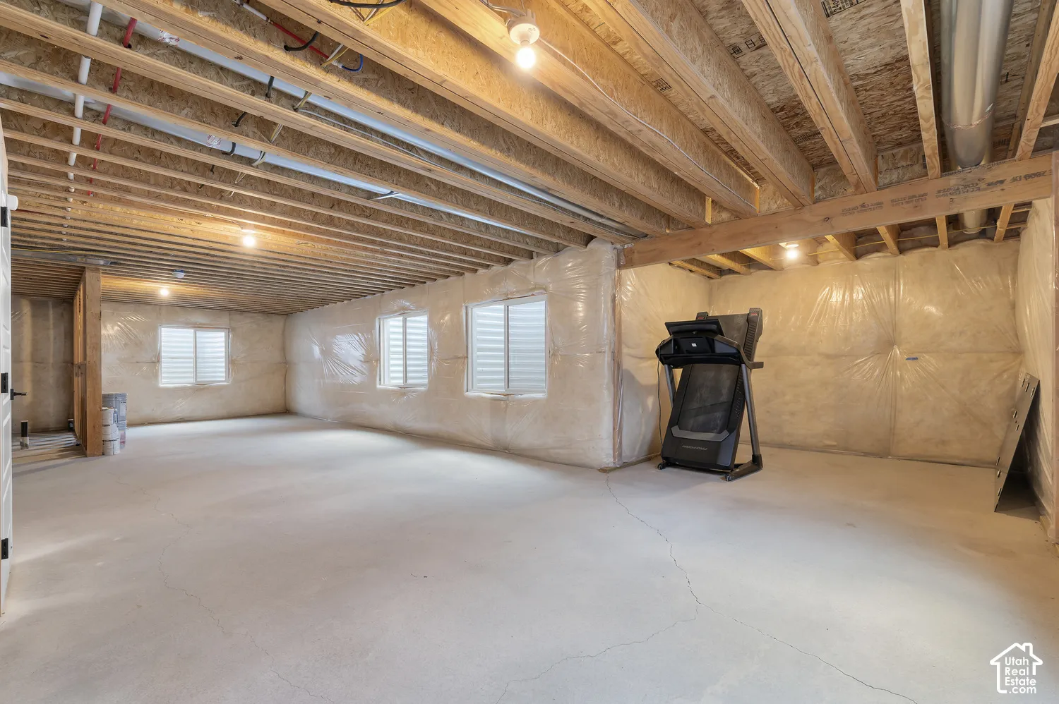 Unfinished expansive space featuring concrete flooring, exposed wood joist ceilings, and multiple egress windows