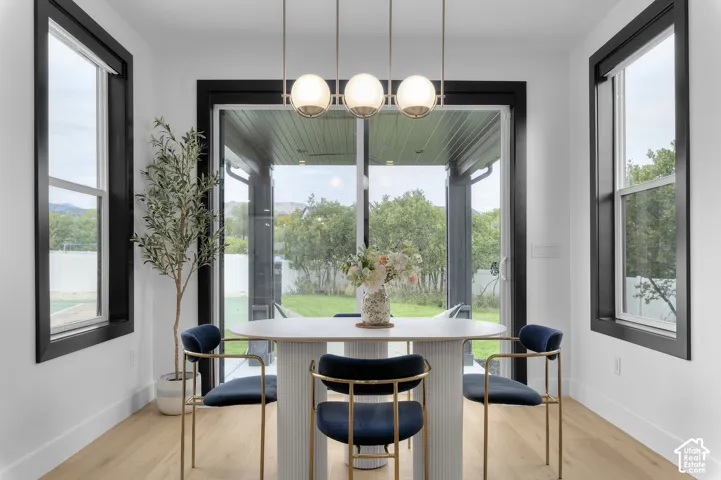 Dining area featuring wood-finish flooring, high-contrast black window trim, a contemporary linear chandelier with frosted globe shades, and sliding glass doors with direct exterior access