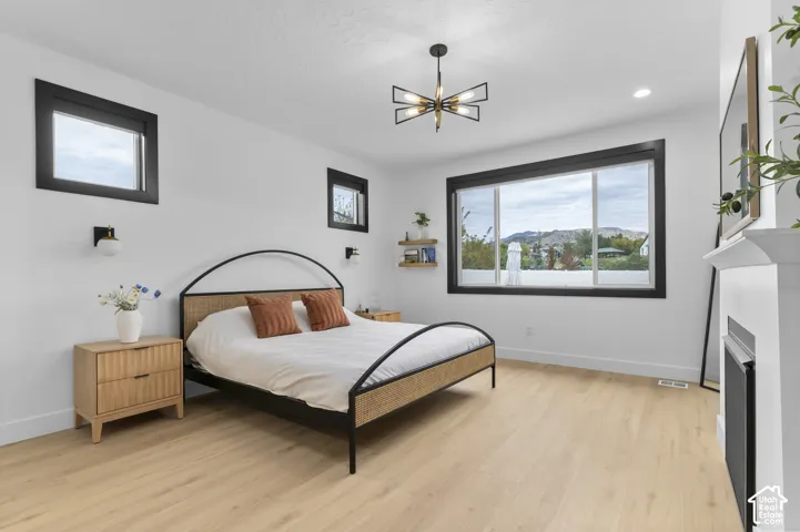 Light-filled space featuring wood-finish flooring, a modern geometric chandelier, custom black-trimmed windows, built-in shelving, and a fireplace