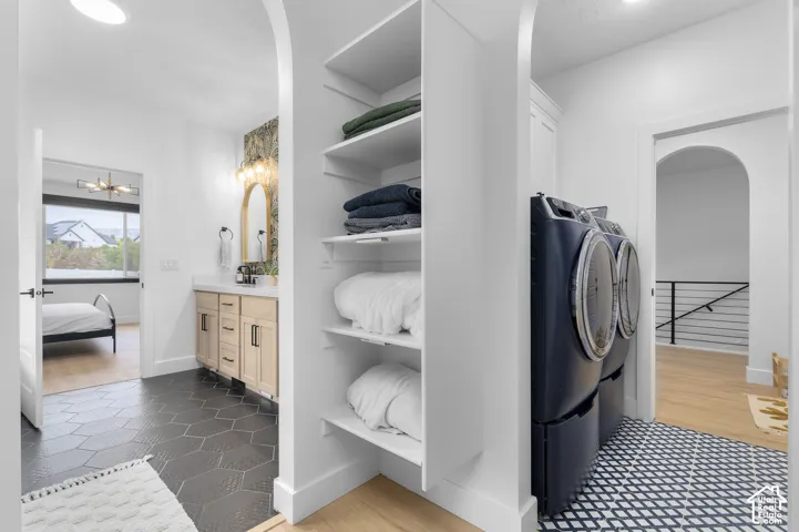 Built-in shelving with multiple storage tiers, vanity featuring a light-toned wood finish and stone countertop, geometric tile flooring, and arched architectural doorways