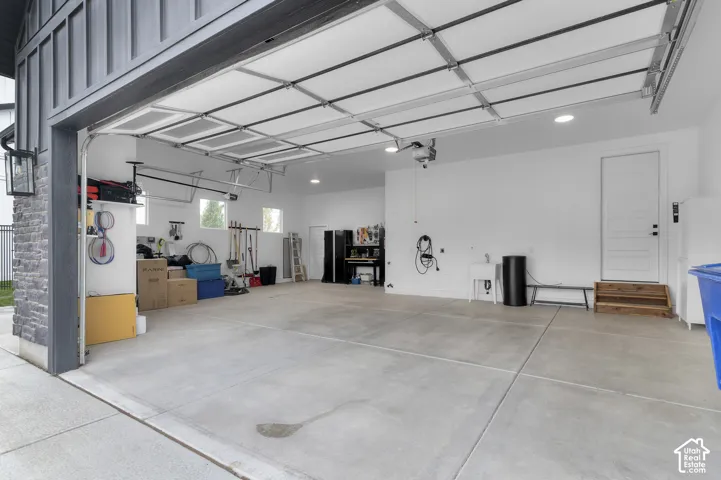 Spacious three-car garage featuring a concrete floor, recessed lighting, utility sink, and exterior door access