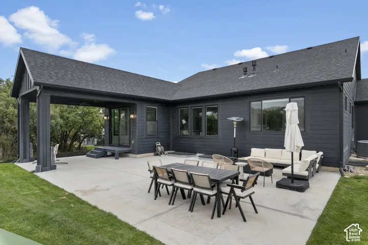 Dark horizontal lap siding exterior featuring a concrete patio, covered outdoor living area, and asphalt shingle roof