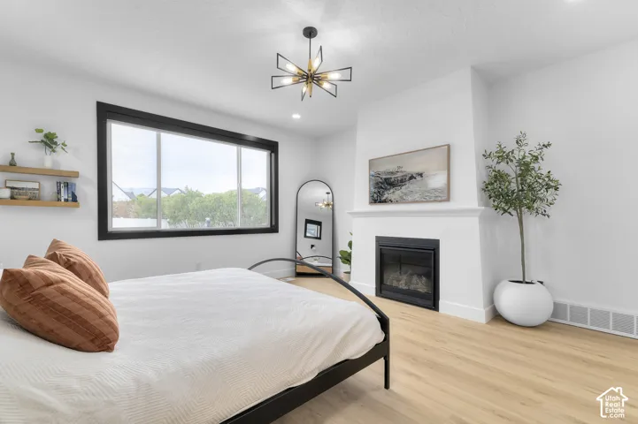 Room featuring wood-finish flooring, a fireplace with a white mantel, a geometric starburst light fixture, and large windows with black trim