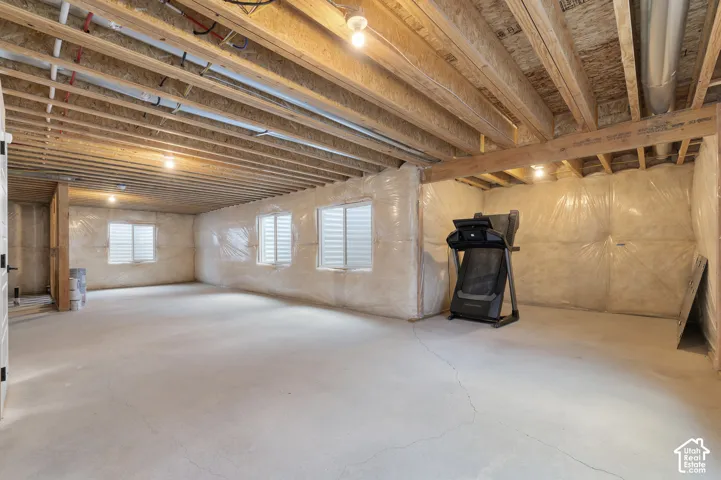 Unfinished expansive space featuring concrete flooring, exposed wood joist ceilings, and multiple egress windows