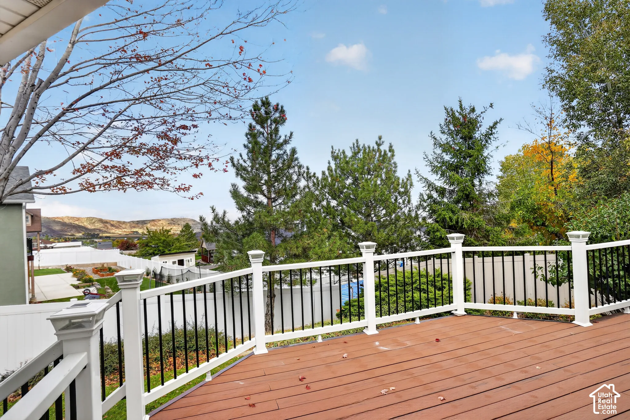 Elevated multi-level deck featuring composite decking, white vinyl railings with integrated solar cap lights, and black metal balusters