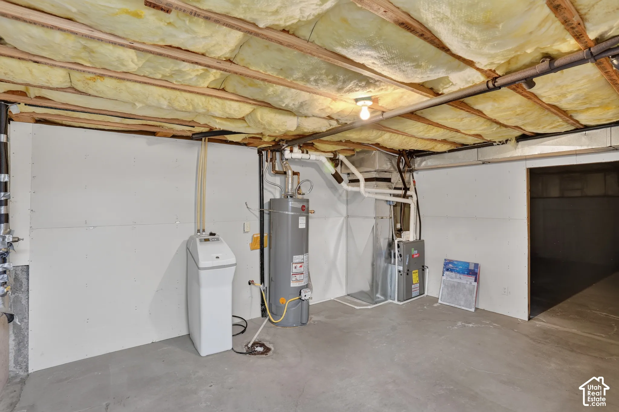 Utility area featuring a water softener, storage tank water heater, forced-air furnace, and concrete flooring