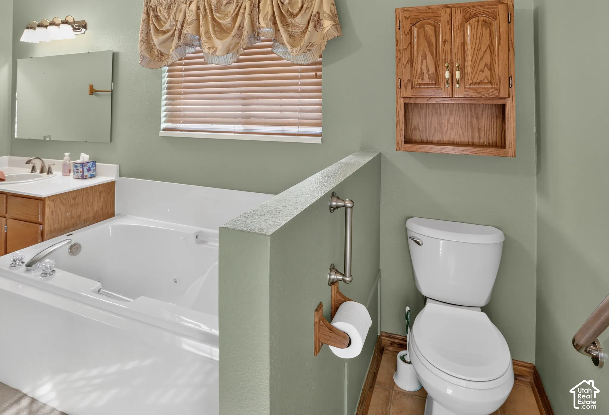 Bathroom featuring a soaking tub, wood-finish cabinetry, wall-mounted storage cabinet, and brushed-nickel hardware